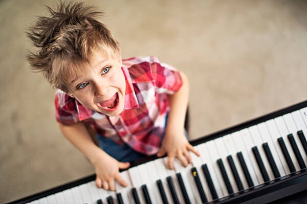 Happy little boy playing piano and singing.